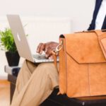Laptop Bag - Person Wearing Blue Suit Beside Crossbody Bag and Using Macbook
