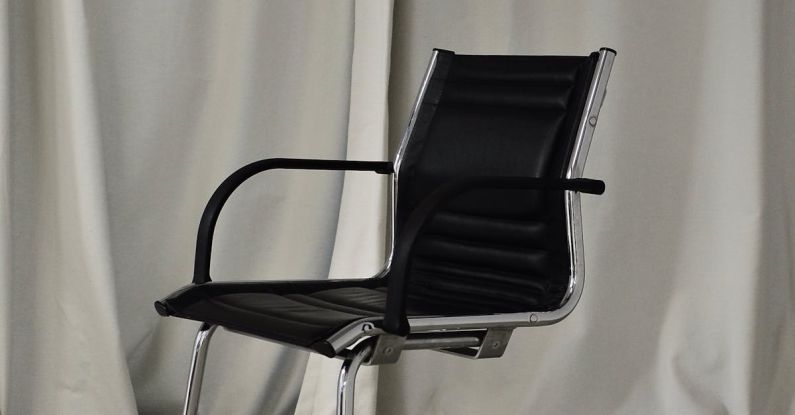 Leather Vs. Fabric - Black chair with leather seat and metal elements placed in light room against long curtain