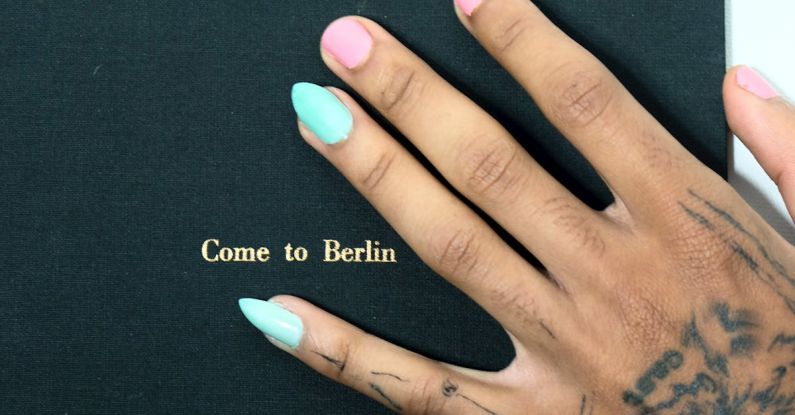 Style Guide Book - Top view of crop unrecognizable informal female with colorful manicure and tattoos with Come To Berlin book with black hardcover