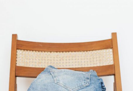 Vintage Jeans - Stack of blue jeans of different shades on modern wooden chair against white wall