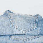 Denim Trends - Pile of denim pants of different shades of blue placed on white shelf