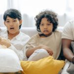 Watch - Interested multiracial family watching TV on sofa together with dog